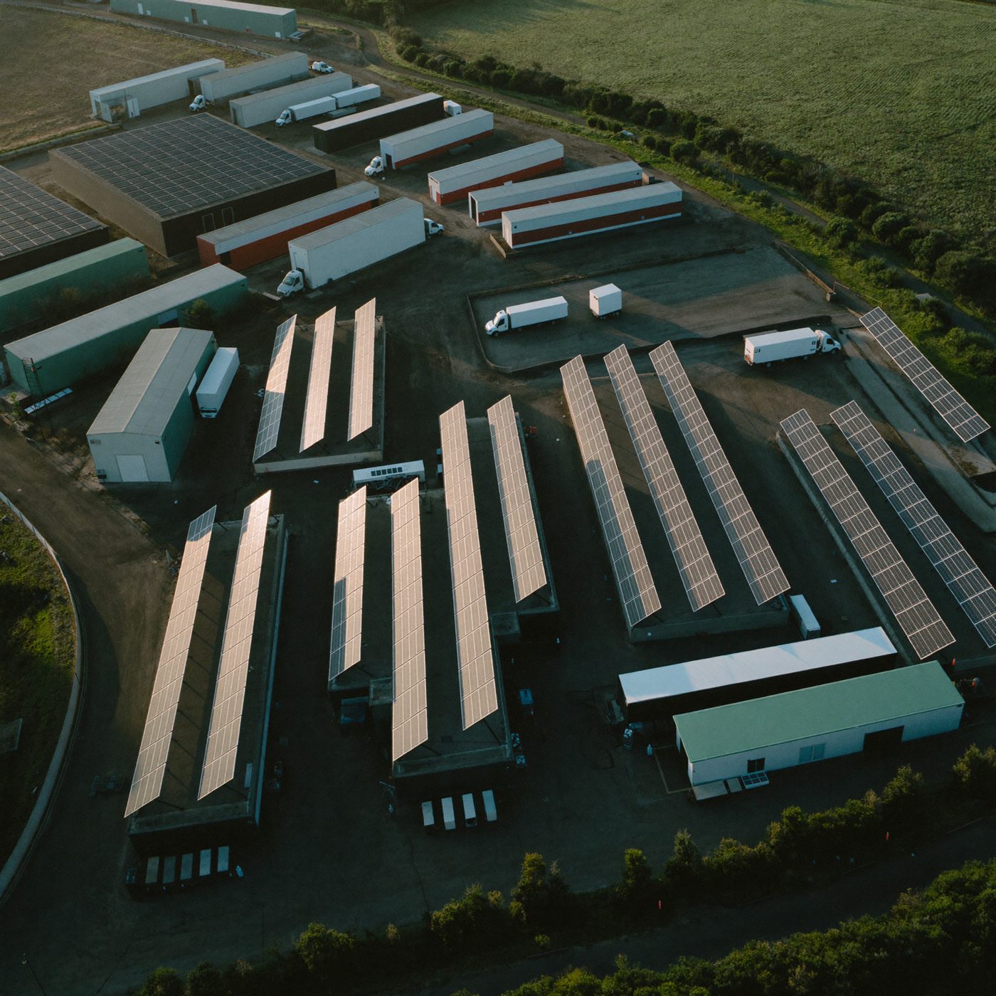 Aerial view of a UK business park with rooftop solar panels at golden hour